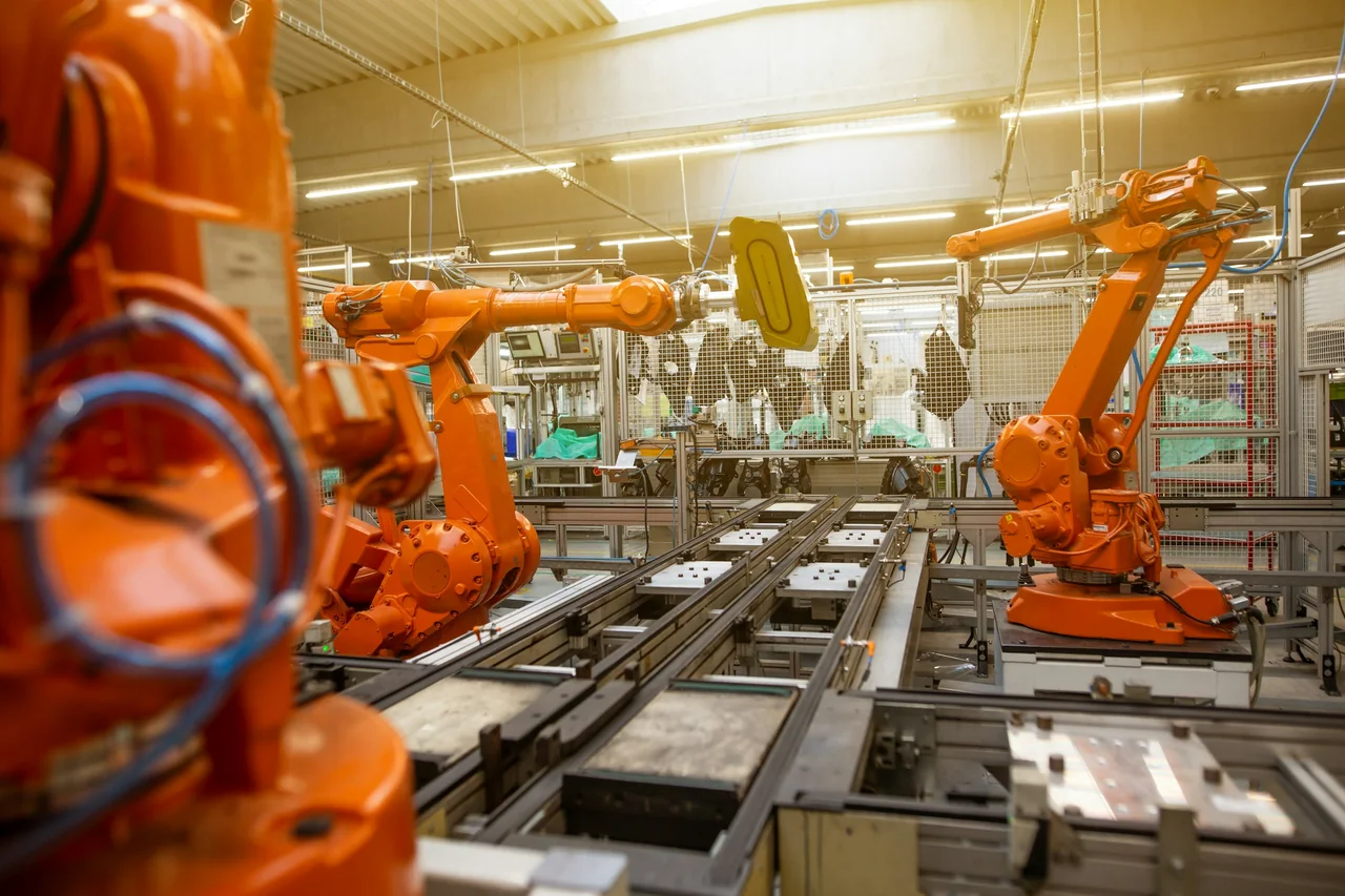Orange industrial robot arms on an automated assembly line